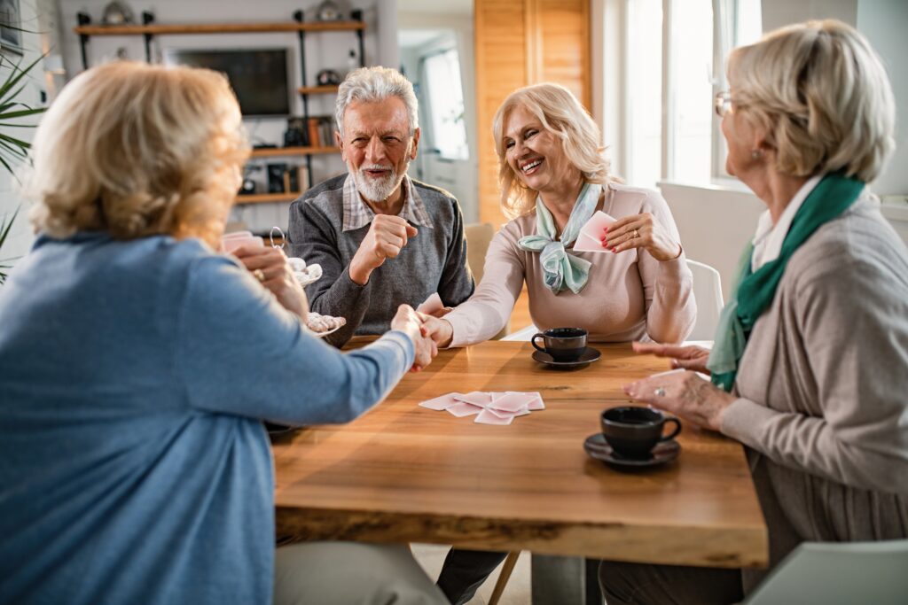 happy-senior-women-handshaking-after-playing-cards-with-their-friends-home